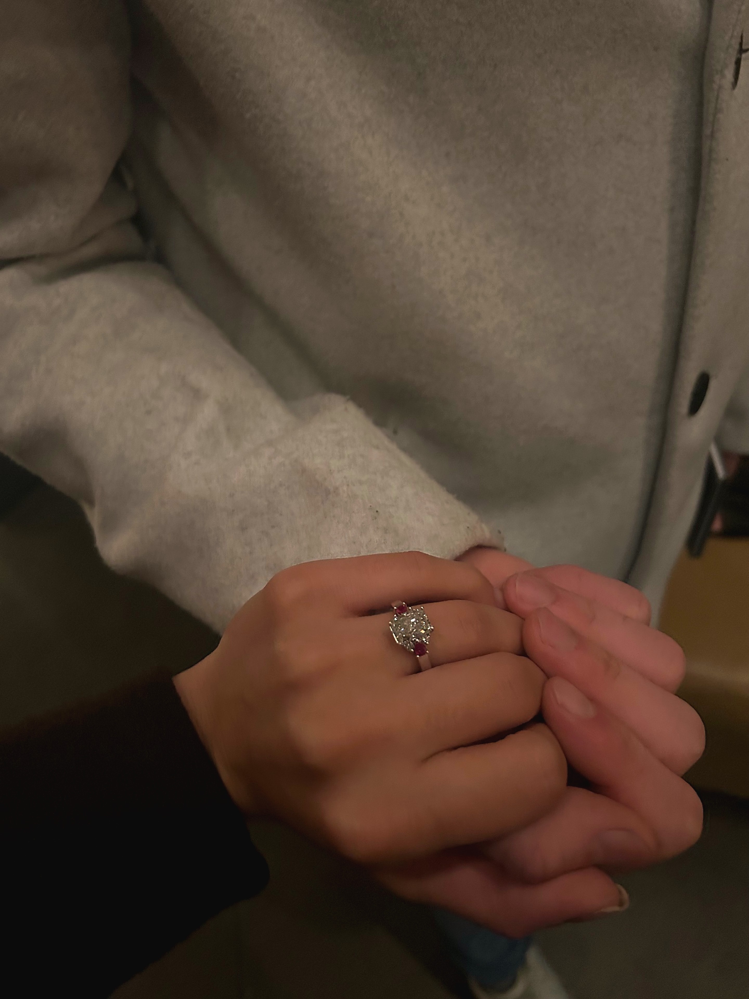Close-up of their hands with the ruby-accented engagement ring