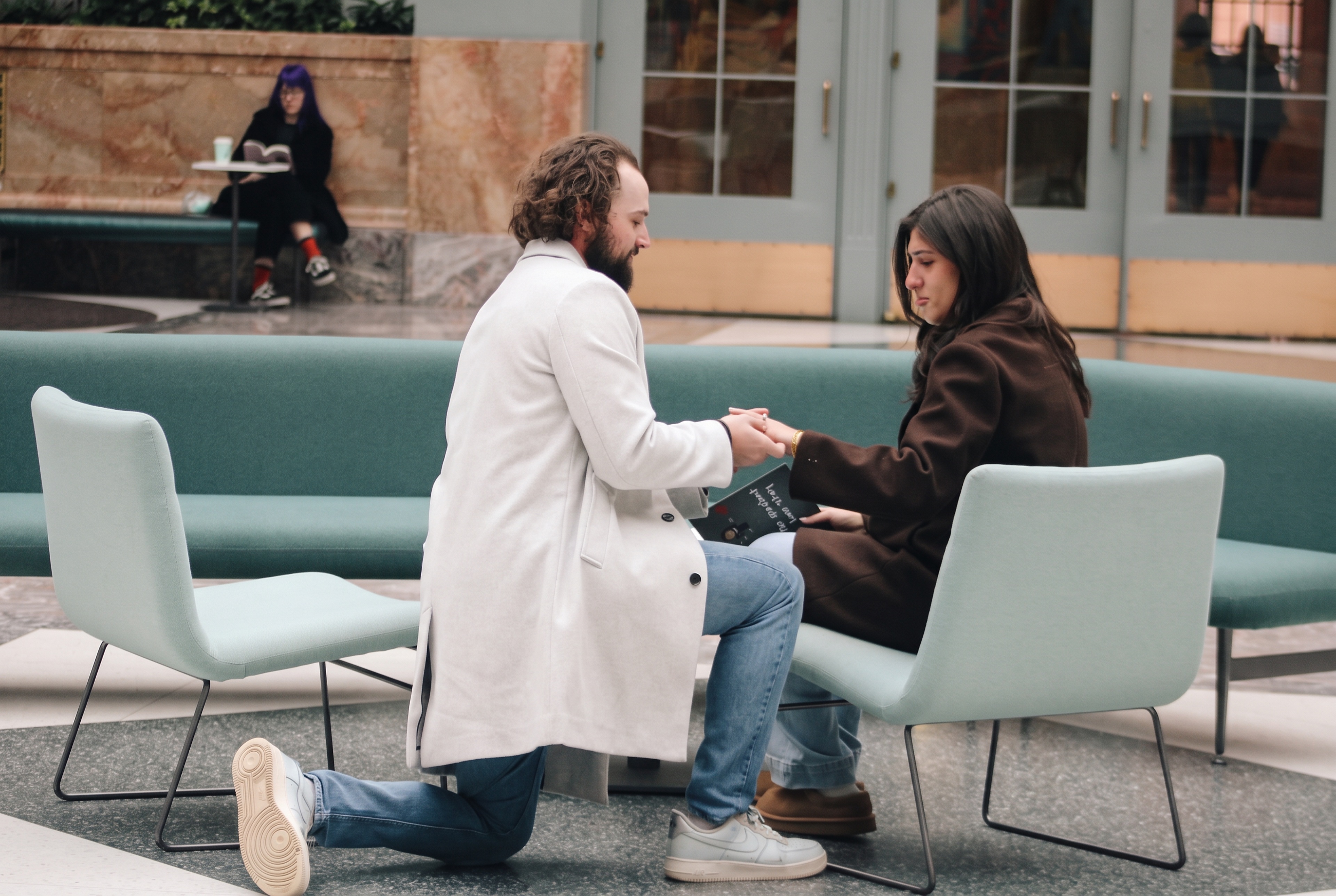 Nick holding Mariella's hands while kneeling during the proposal