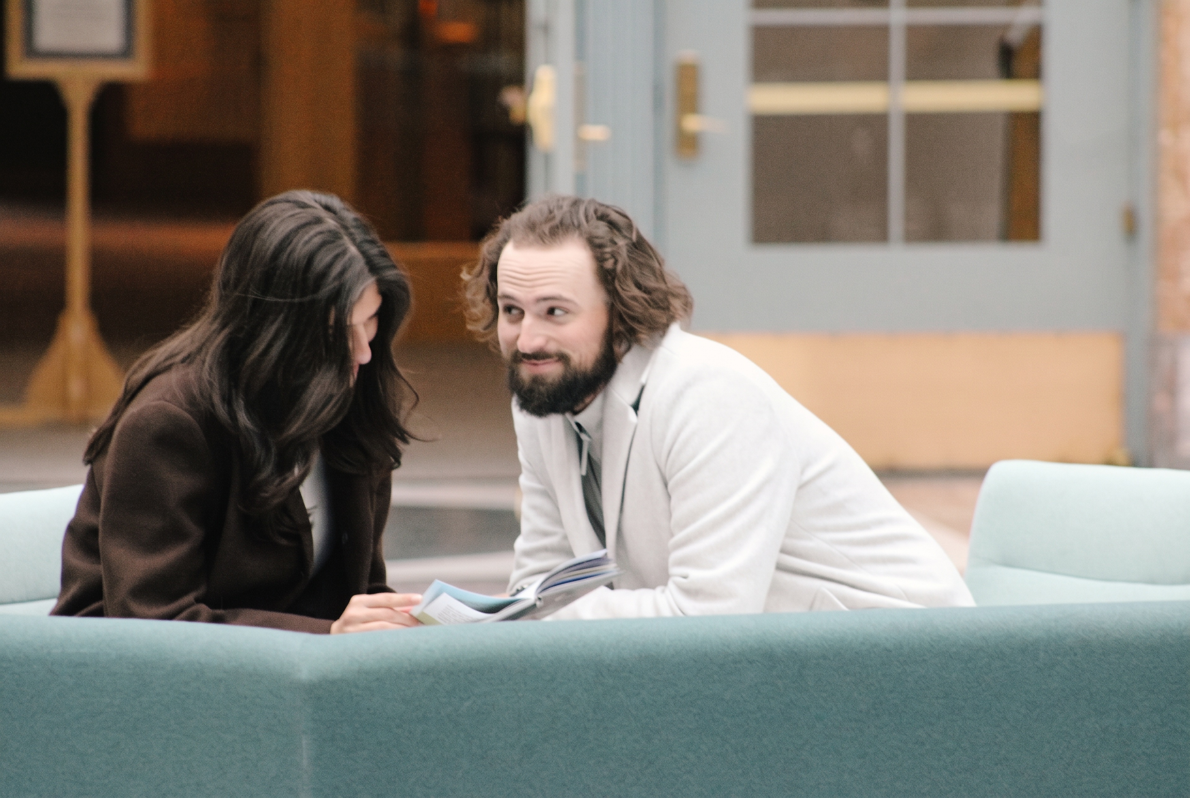 Nick and Mariella sitting together looking through a book in the atrium