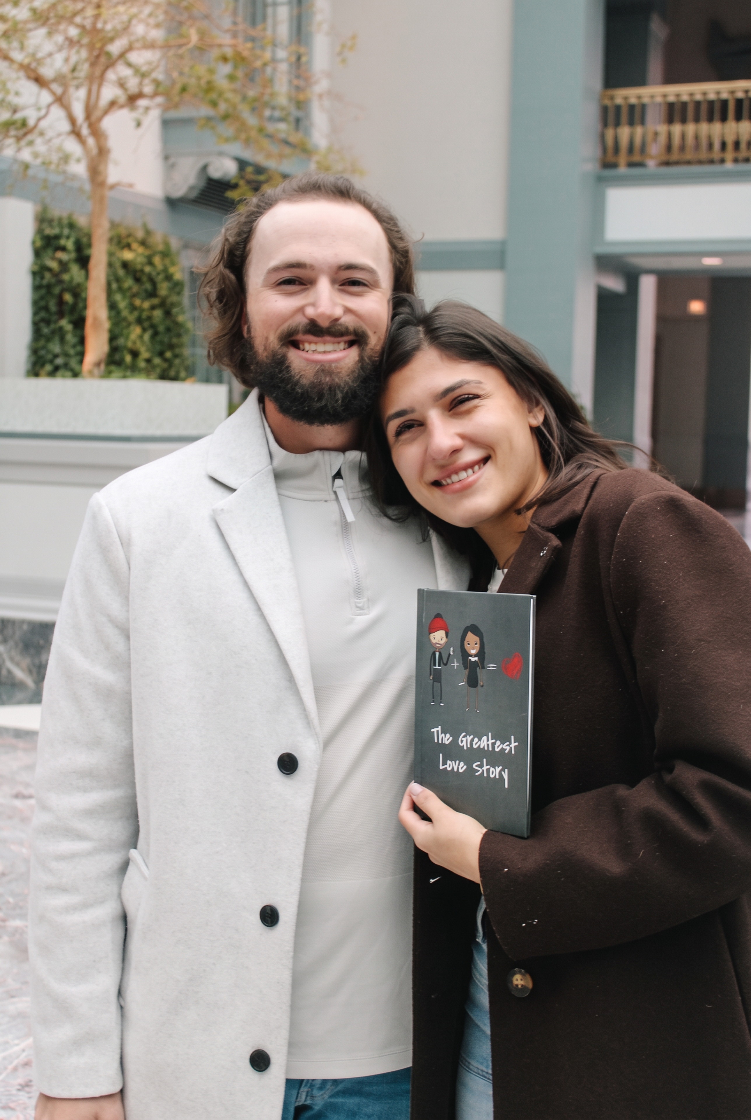 Nick and Mariella smiling while posing with a book